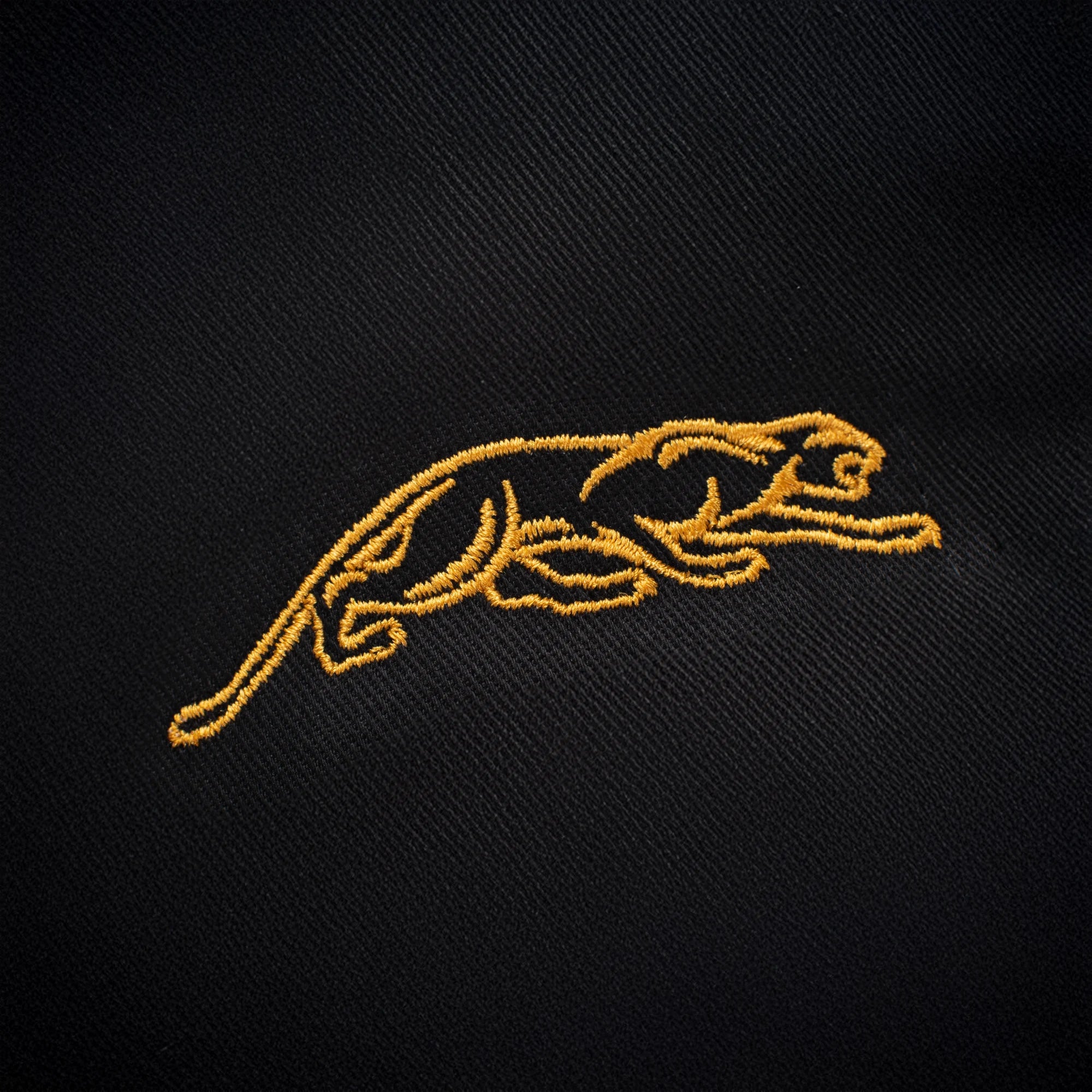 Gold embroidered panther logo against a black background.