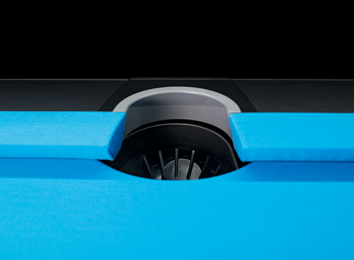 Close-up of a blue pool table with a black pocket.