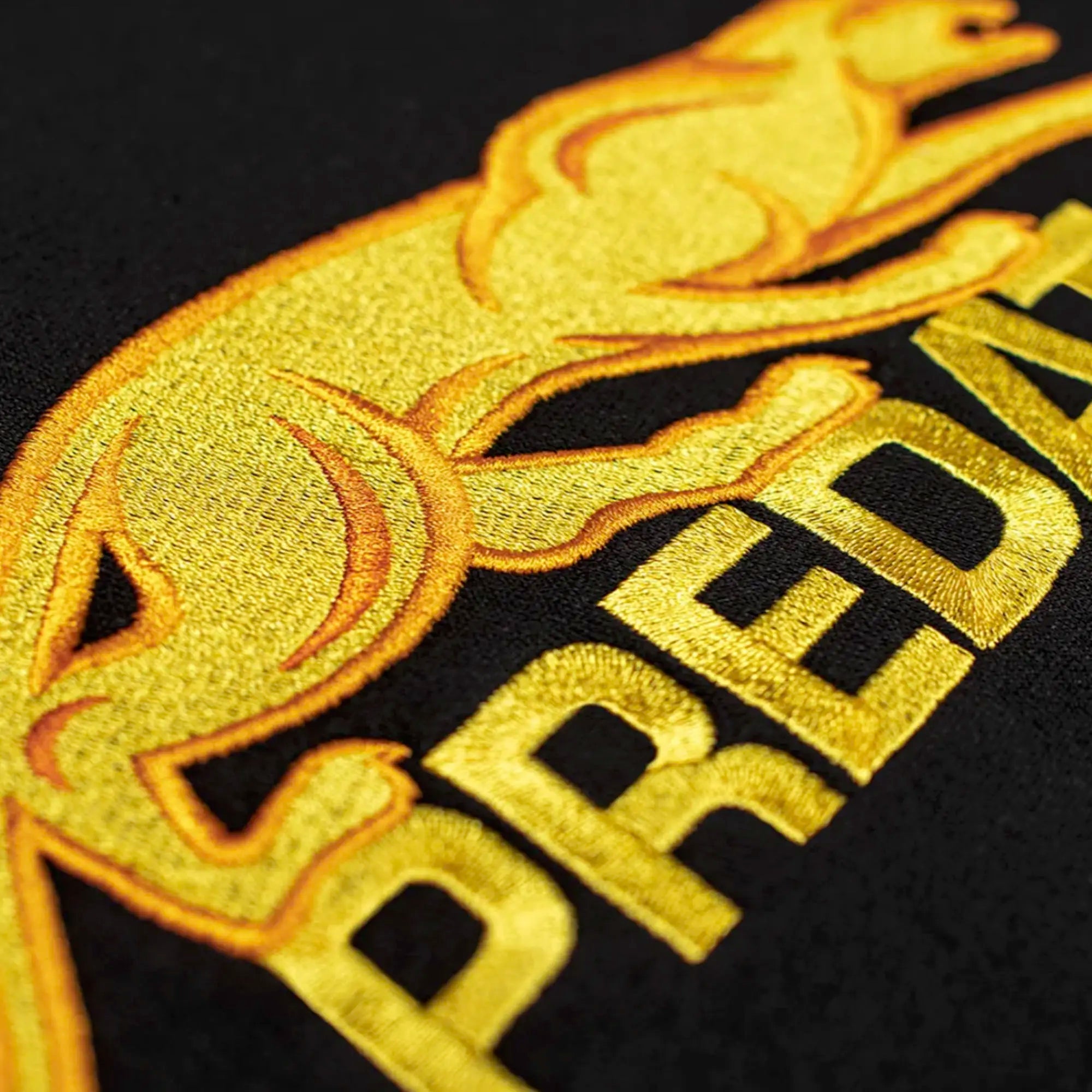Close-up of gold embroidered Predator logo against a black background.