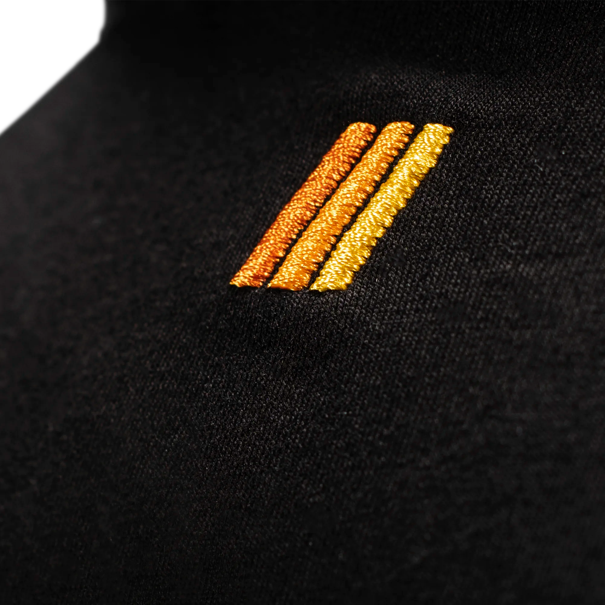 Close-up of a black garment with gold and bronze embroidered stripes.