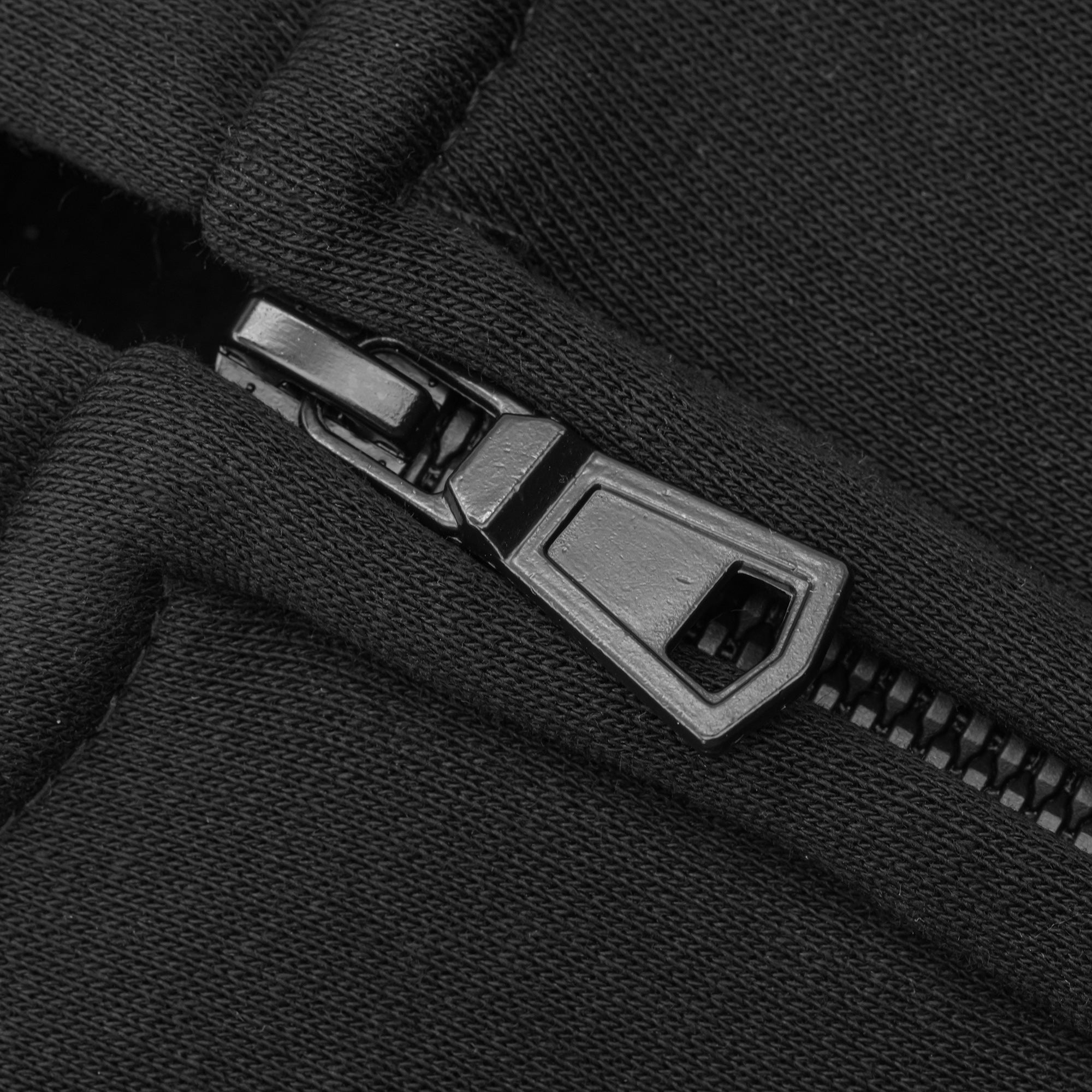 Close-up of a zipper on a black fabric background.