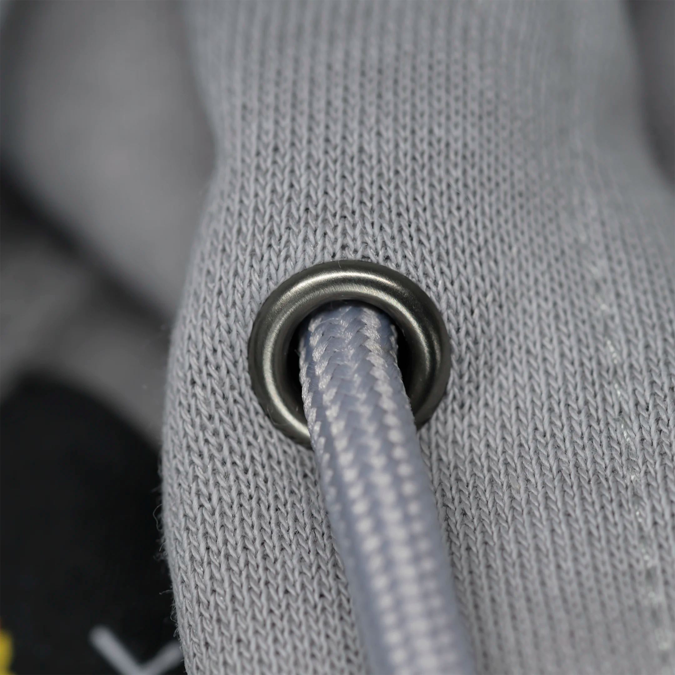 Close-up of a gray textured fabric with a metal grommet.