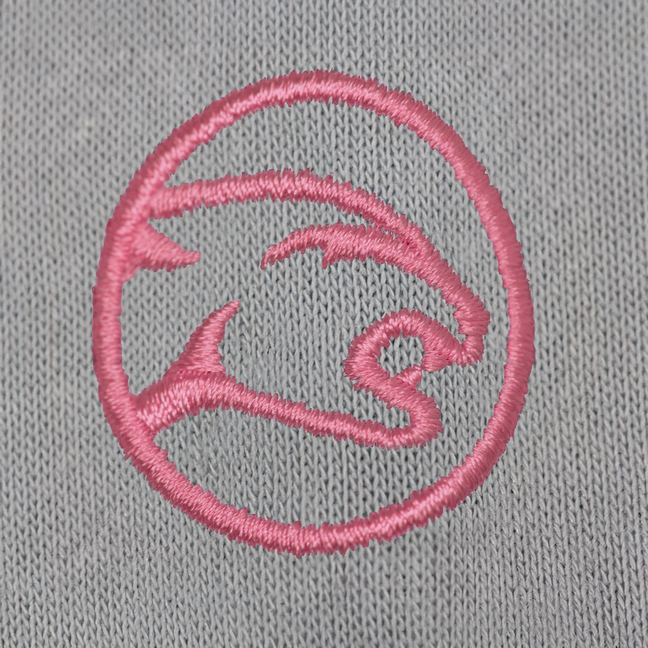 Pink embroidered cat head logo against a grey fabric background.