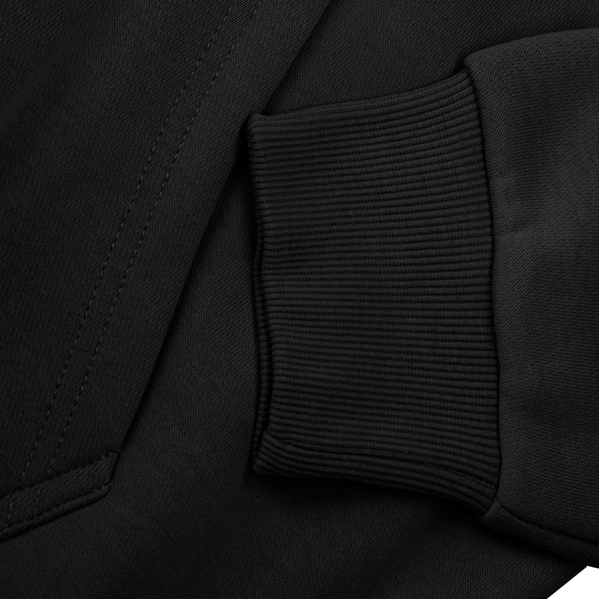 Close-up of black hoodie cuff and pocket against a black fabric background.