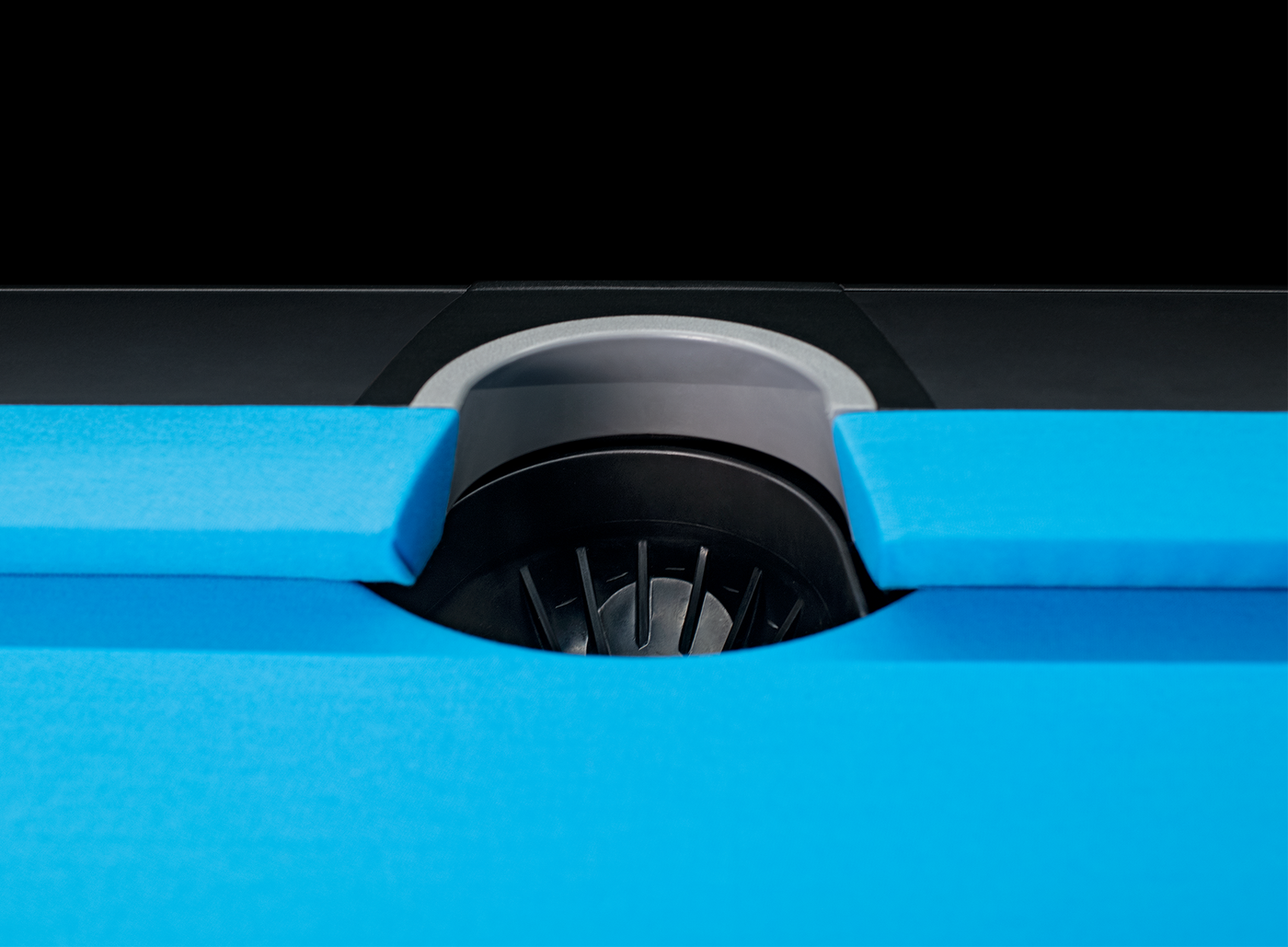 Close-up of a blue pool table with a black pocket.