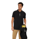 Man wearing a black polo shirt with a zipper and beige pants, holding a black jacket with yellow text.