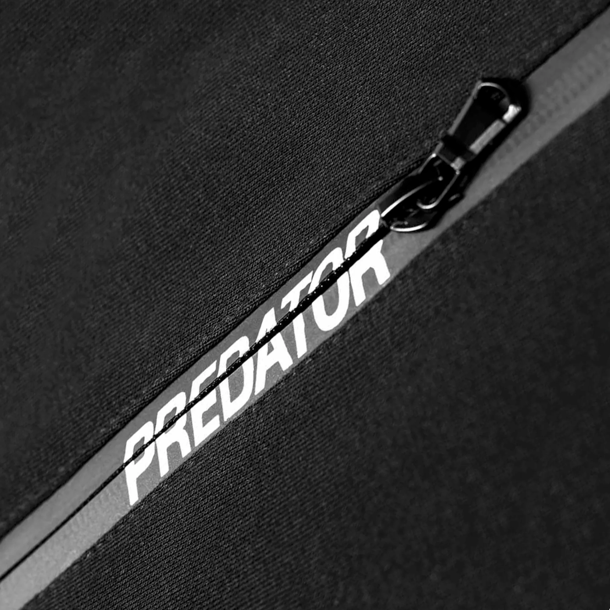 Close-up of a black surface with 'Predator' branding on a zipper.