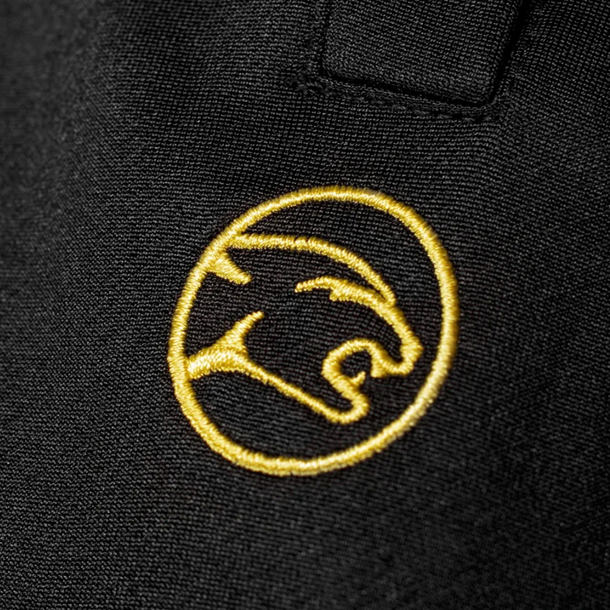 Yellow embroidered circular cat head logo against a black fabric background.