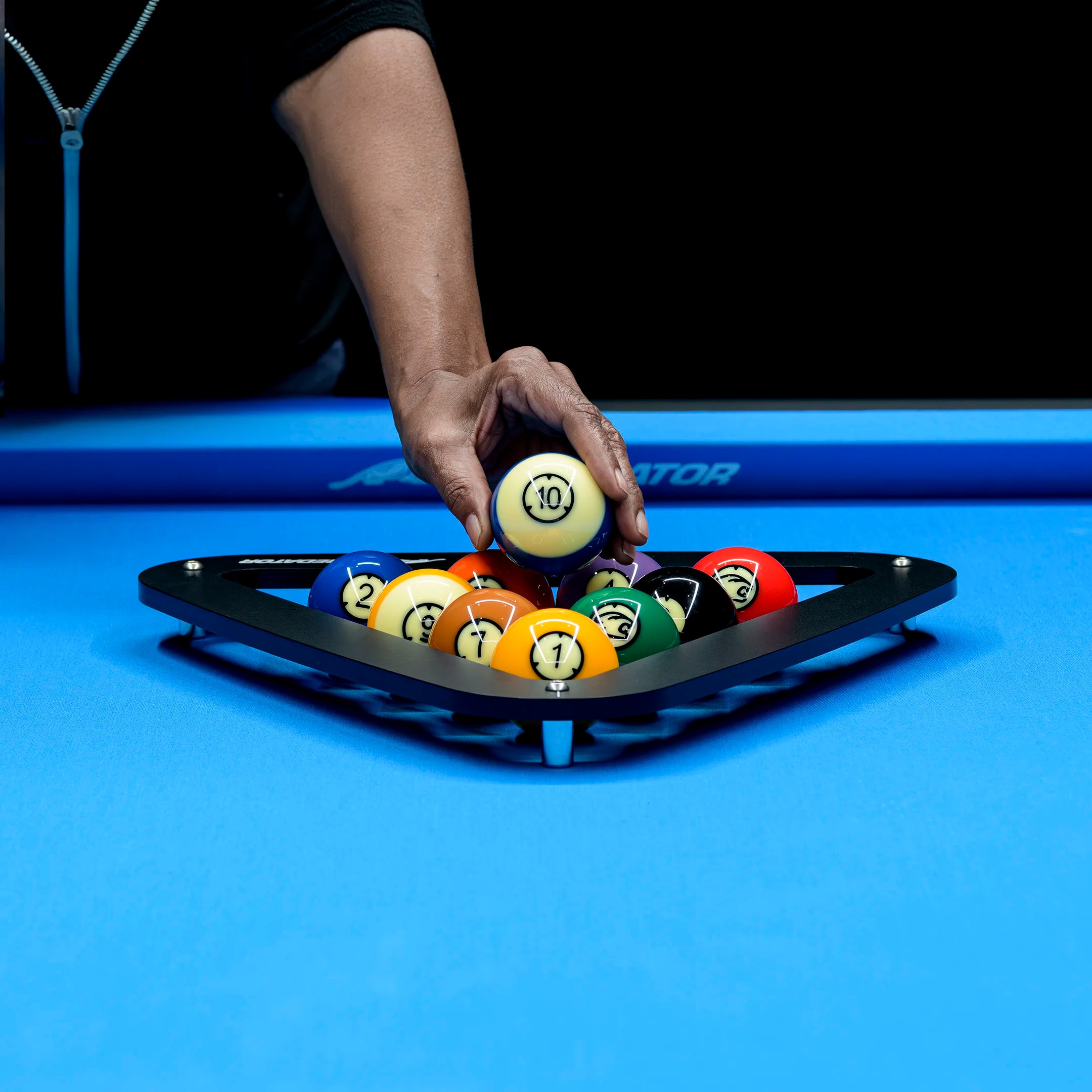 Person arranging pool balls on a blue pool table
