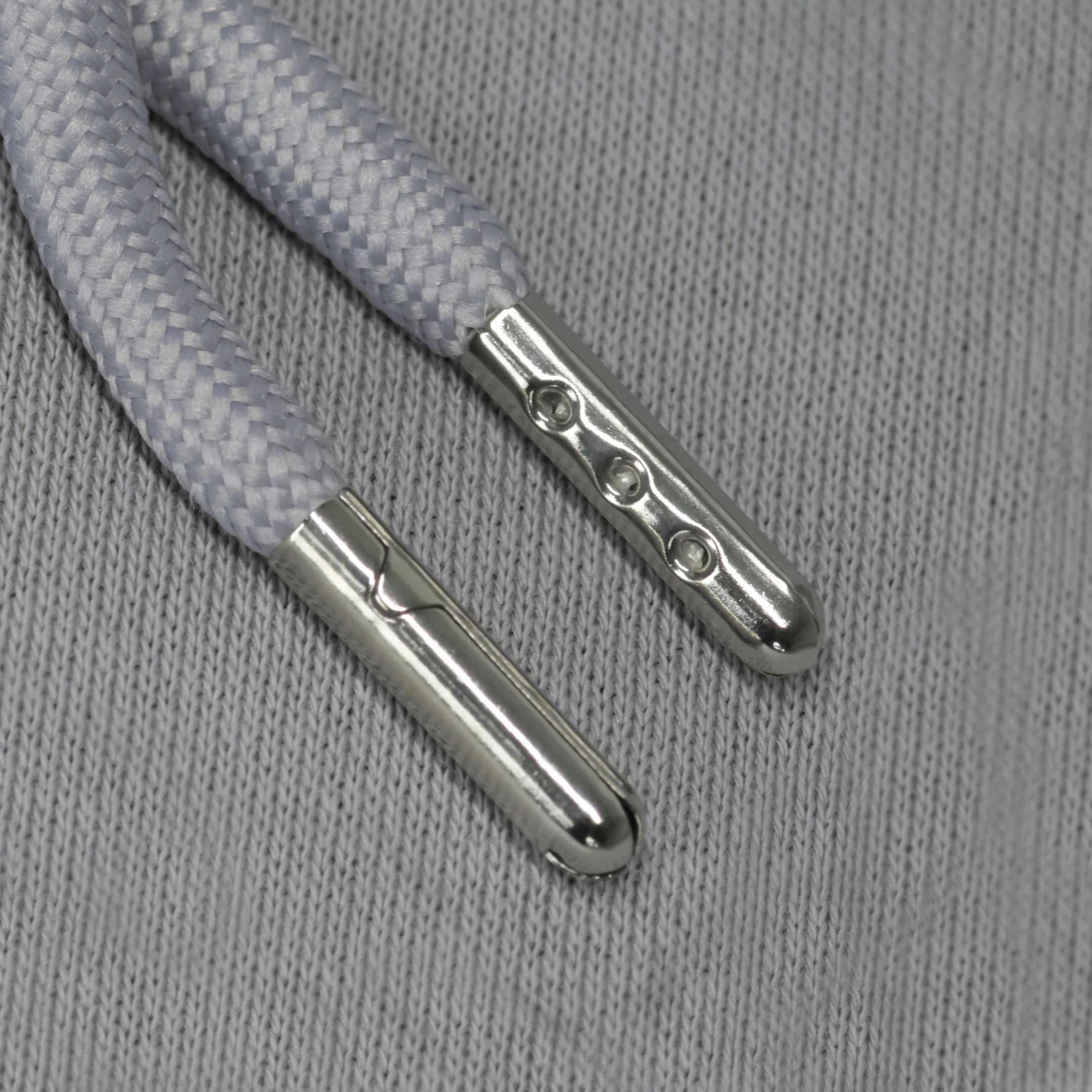 Silver aglets against a grey fabric background.