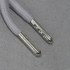 Silver aglets against a grey fabric background.