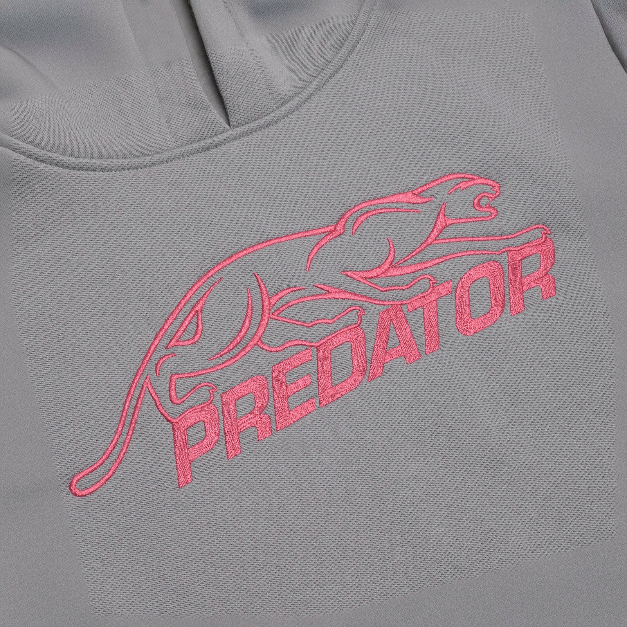 Pink embroidered Predator logo against a grey sweatshirt background.