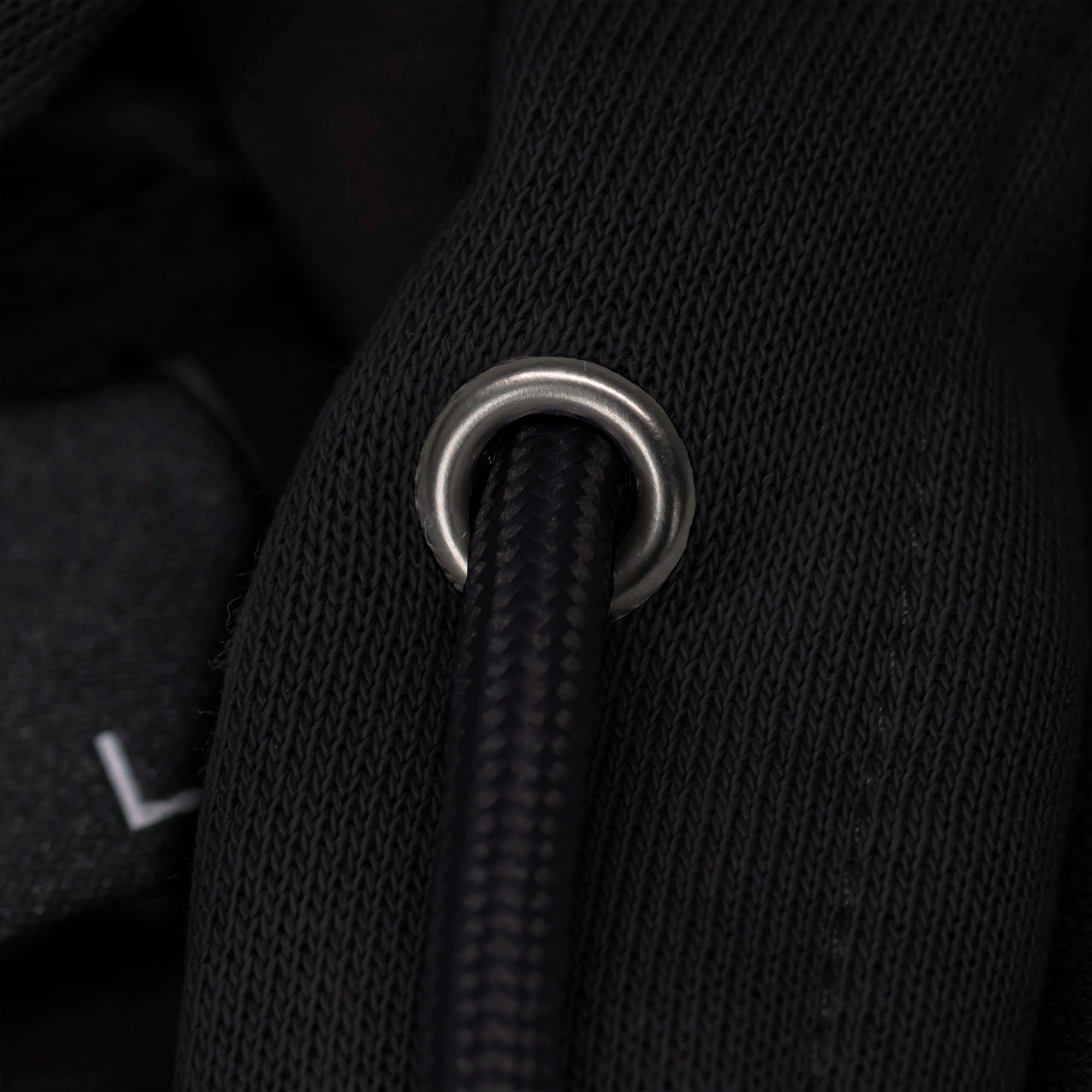 Close-up of a black drawstring with a metal ring on a dark background.