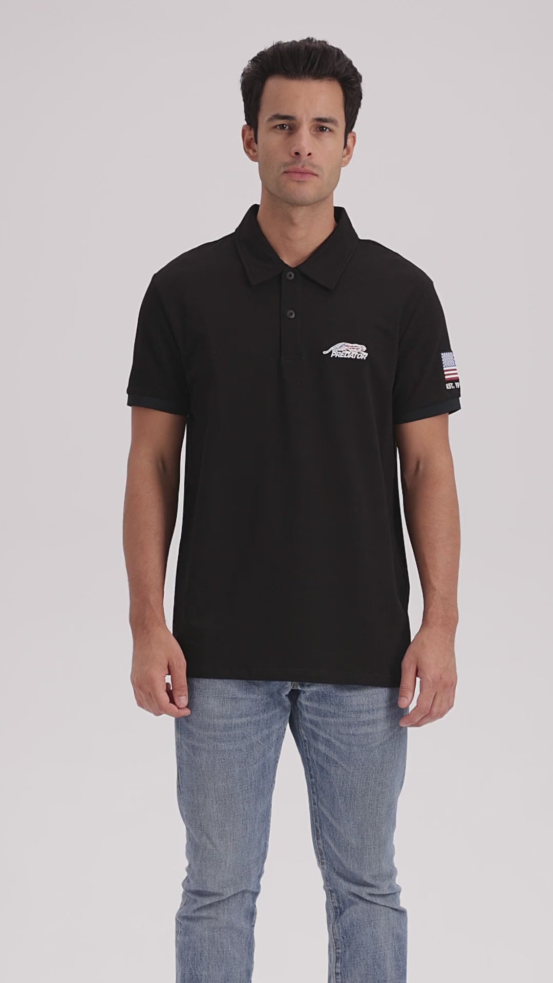 Man with dark hair wearing blue jeans and a black polo shirt with a United States flag PREDATOR logo